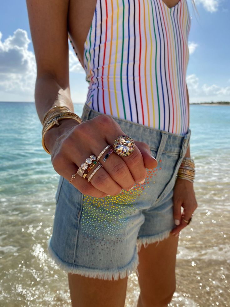 Close‑up of diamond rings and fine jewellery worn at a beach setting — elegant summer travel look